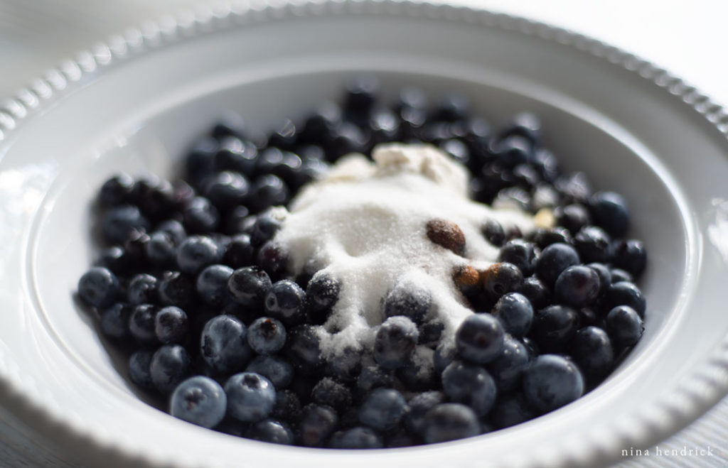 Creating Blueberry Crostata filling. Blueberries and sugar in a bowl.