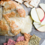 cheese oozing from baked brie with tortilla chips and apples