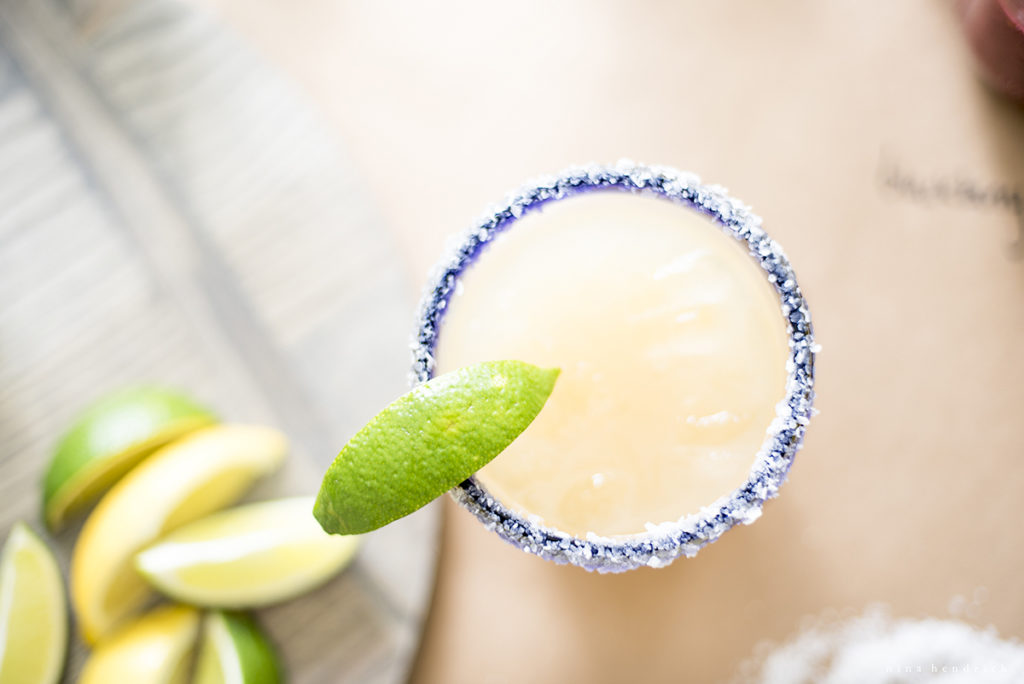 overhead of classic margarita with salt rim and limes